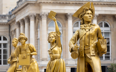 Les statues des femmes en or Jeanne Barret, Olympe de Gouges et Alice Guy devant l'Assemblée Nationale. 