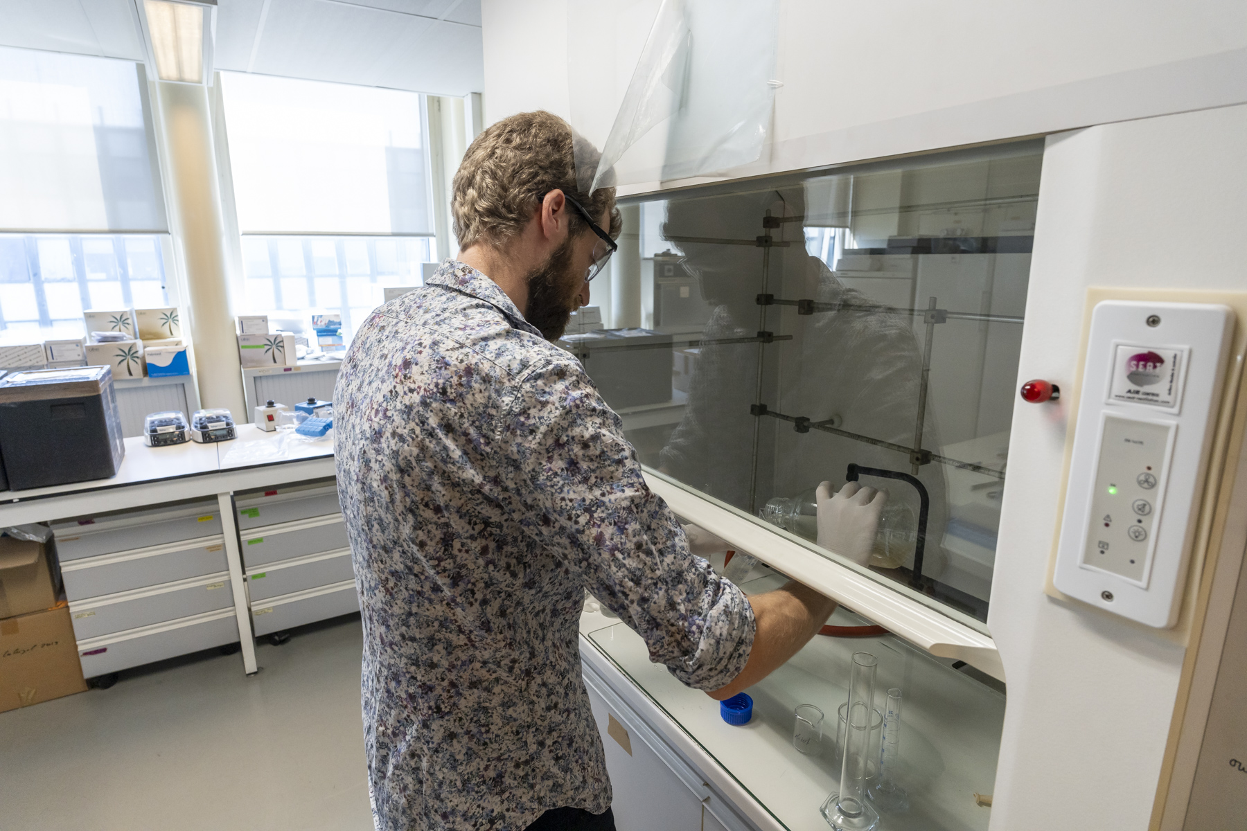 Thomas Thiebault, chercheur à Sorbonne Université, entrain d'analyser des eaux usées (dans un petit flacon, derrière une vitre) 
