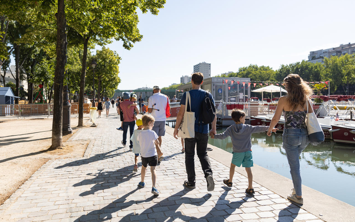 une famille de dos en balade sur les quais de Seine par une journée ensoleillée