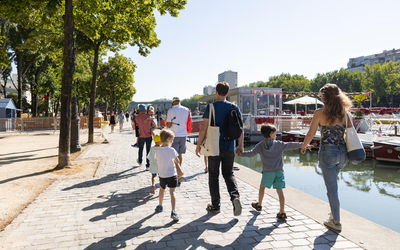 une famille de dos en balade sur les quais de Seine par une journée ensoleillée