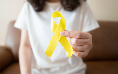 Une femme tenant dans ses mains un ruban jaune , en guise de sensibilisation au cancer des os, au cancer de la vessie et à l'endométriose