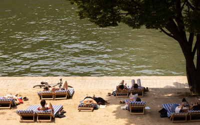 Des personnes se reposent sur des transat  posés sur le sable de Paris Plages, en bordure de Seine.