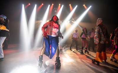 Une femme sur des patins danse sur une piste au milieu d'autres personnes