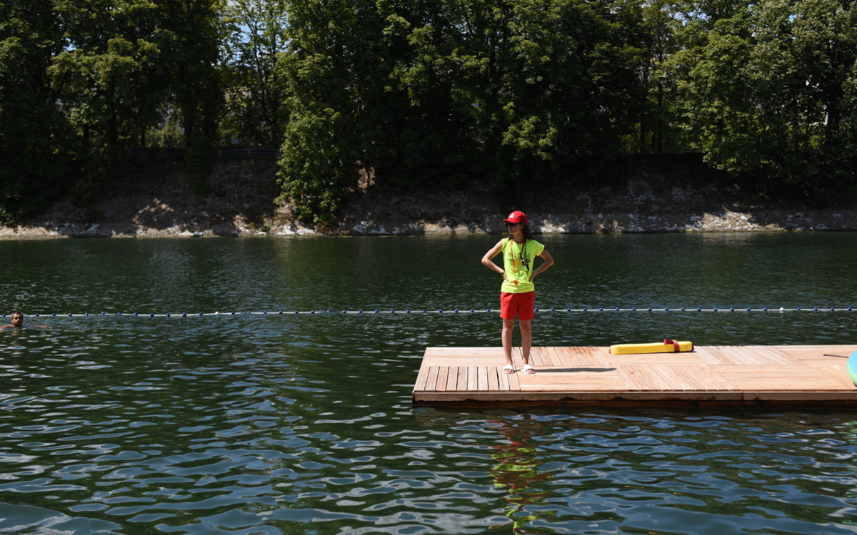 Habillée d'une casquette rouge et d'un tee shirt jaune fluo, une sauveteuse observe le bassin de nage du site de baignade de Grenelle.