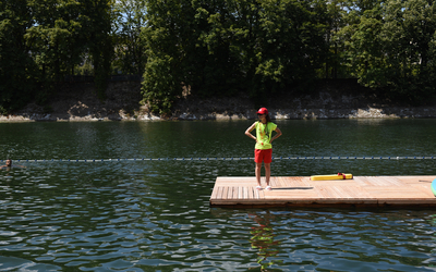 Habillée d'une casquette rouge et d'un tee shirt jaune fluo, une sauveteuse observe le bassin de nage du site de baignade de Grenelle.