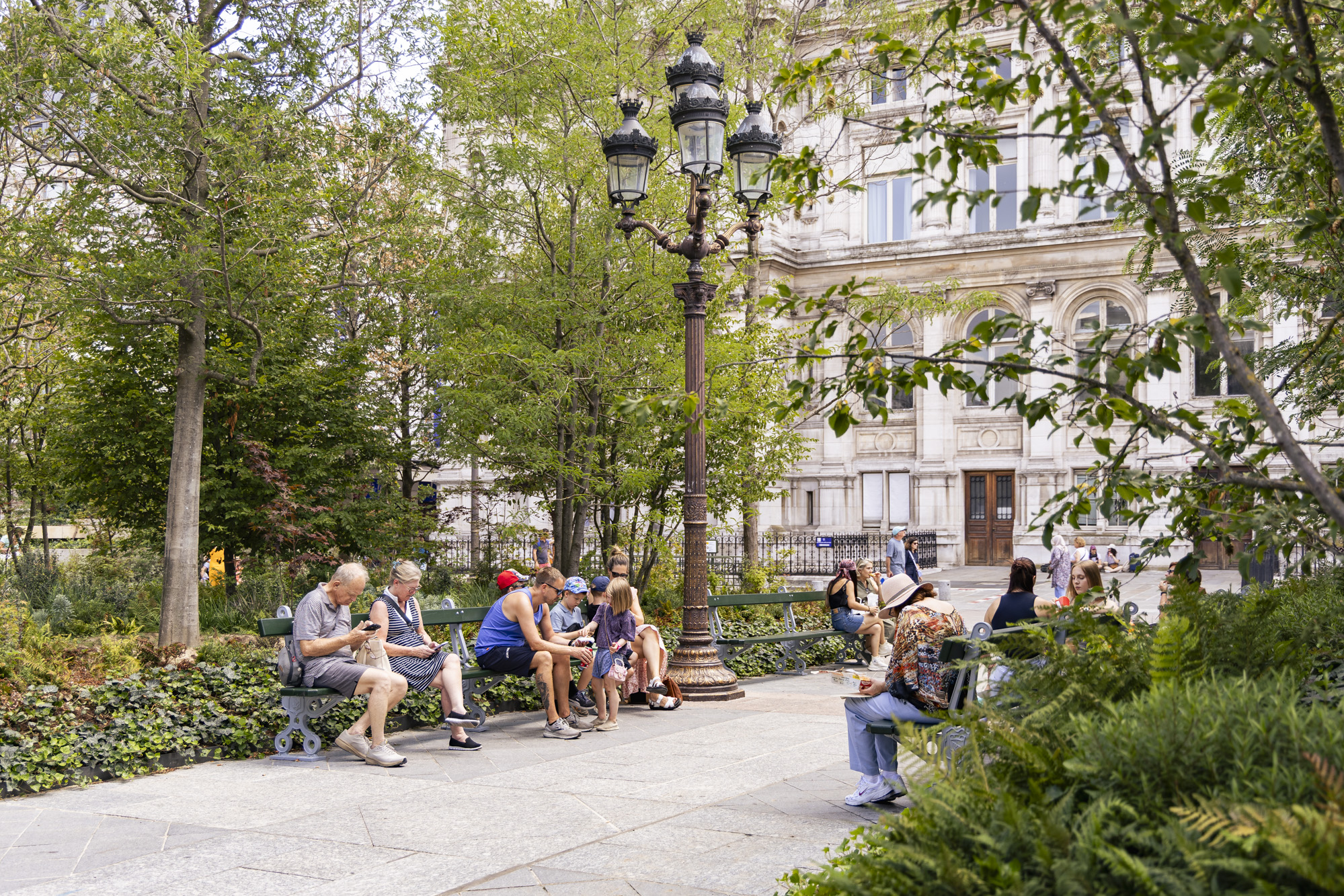 Des personnes se reposent sur les bancs de la foret urbaine. 