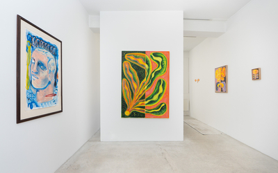 Des toiles aux couleurs vibrantes accrochées sur un mur d'exposition blanc