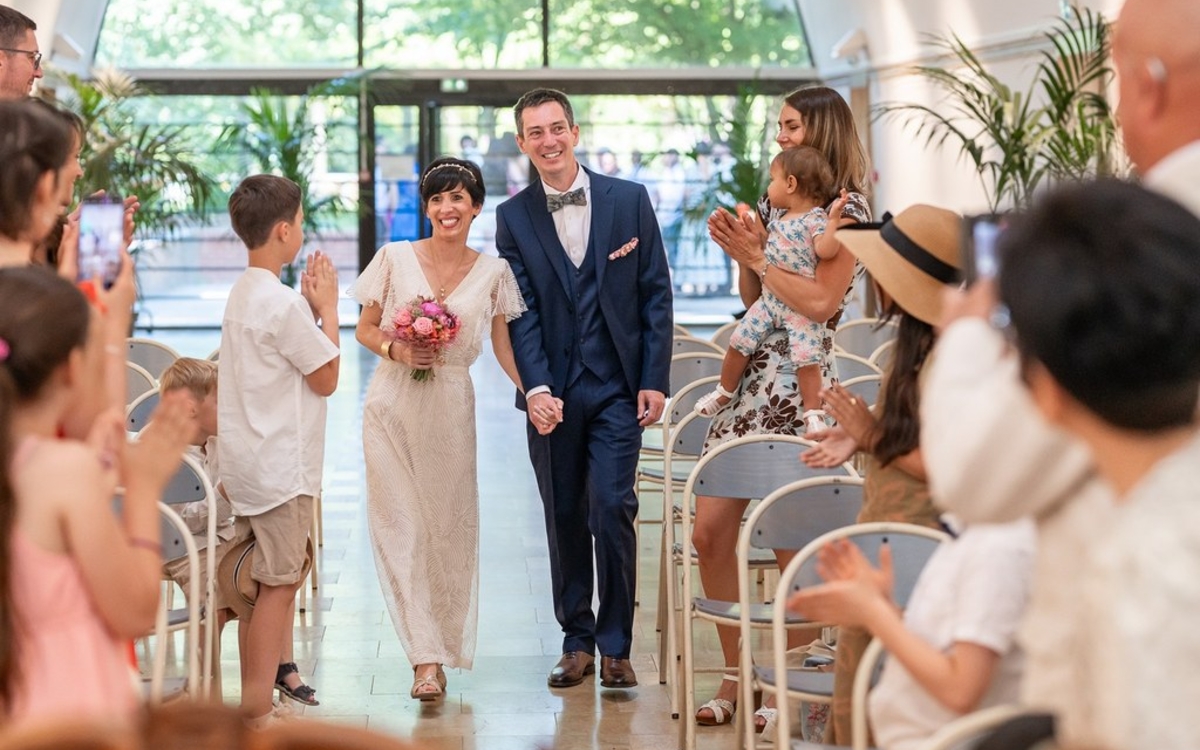Deux jeunes mariés remonte l'allée de la salle de  mariage sous les applaudissements de leurs invités