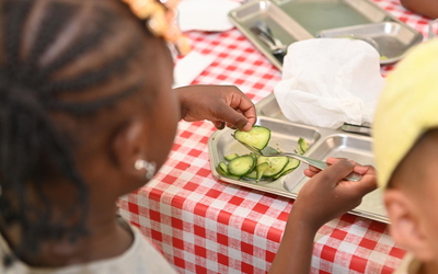 une enfant mangeant des courgettes à la cantine