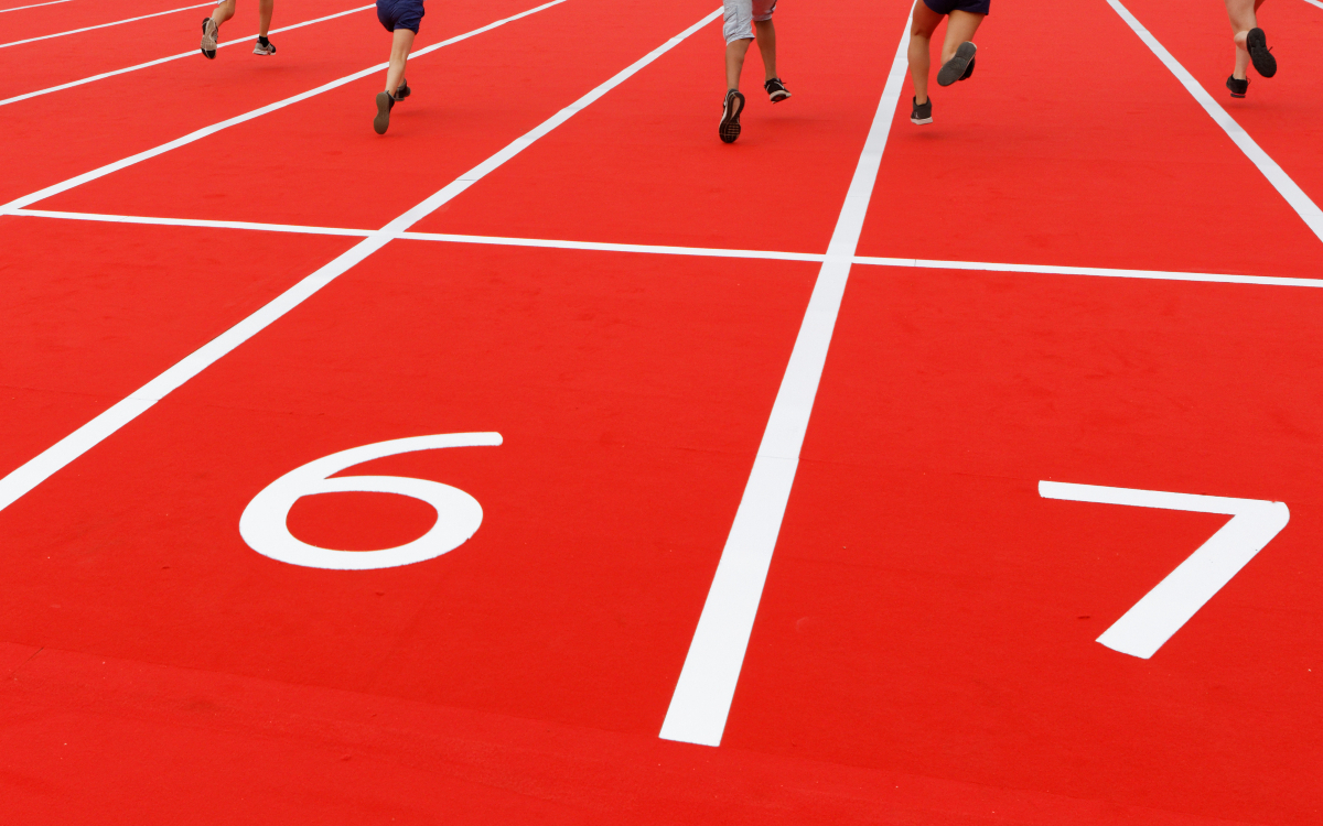 Des enfants courant sur une piste d'athlétisme. 