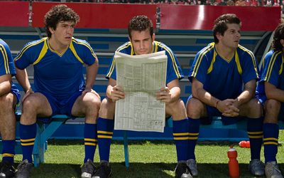 Un footballeur lisant le journal sur le banc de touche. 