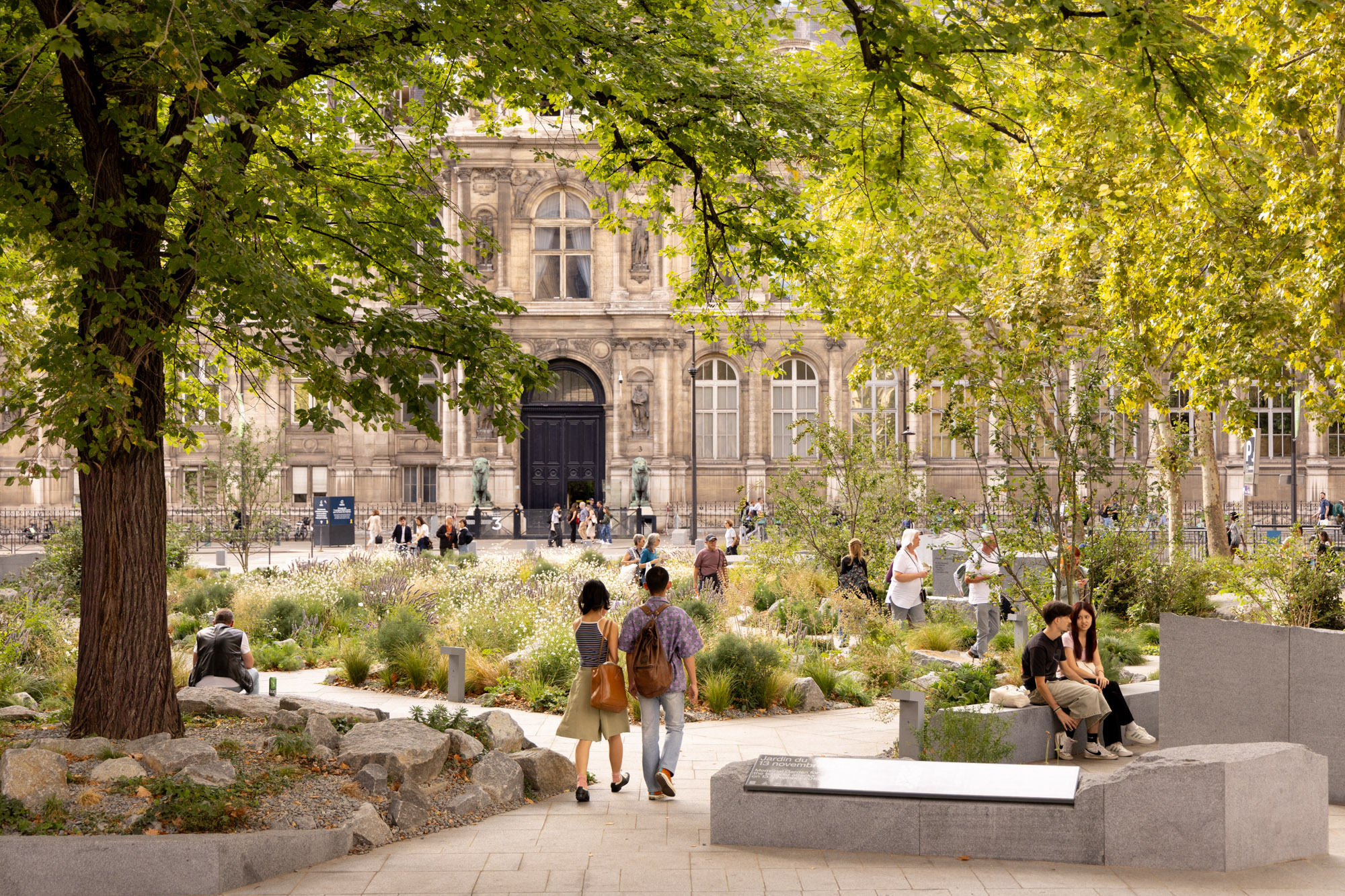 Des personnes se promènent et viennent se recueillir dans le jardin mémoriel en hommage aux victimes des attentats du 13 novembre 2015 sur la place Saint-Gervais.