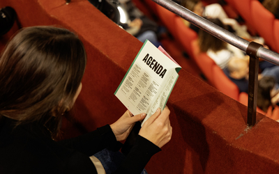 Une personne lit un agenda culturel dans une salle de théatre.