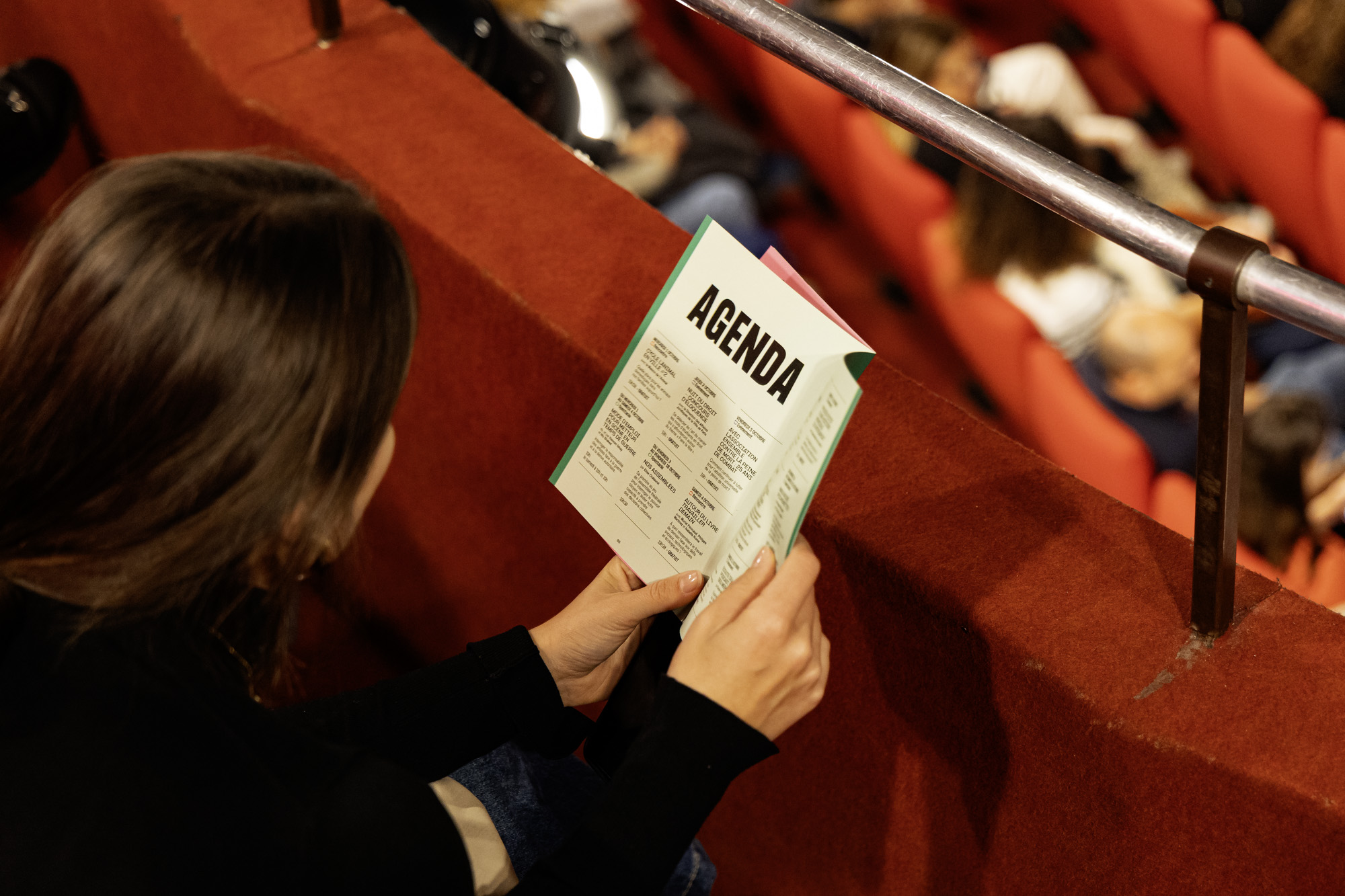 Une personne lit un agenda culturel dans une salle de théatre.