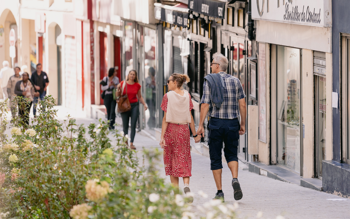 Des personnes foulent le sol de la rue Mouffetard fraichement végétalisée.