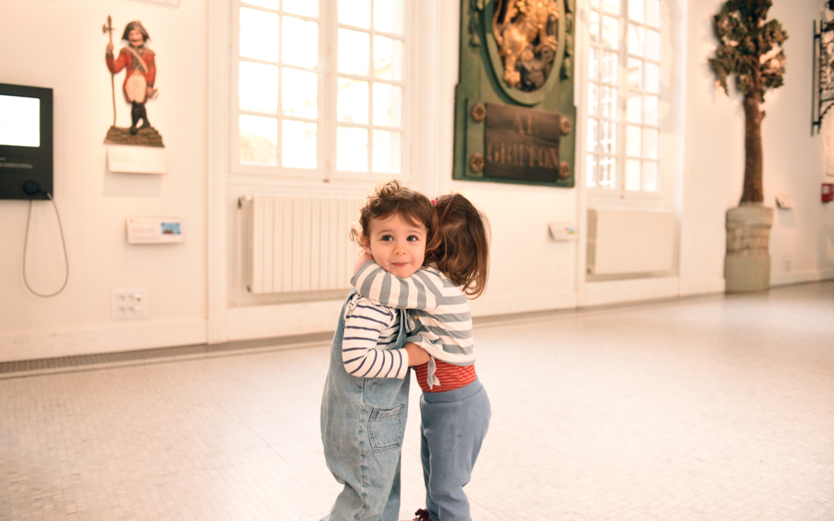 Deux enfants se font un calin dans la salle des enseignes du Musée Carnavalet. 