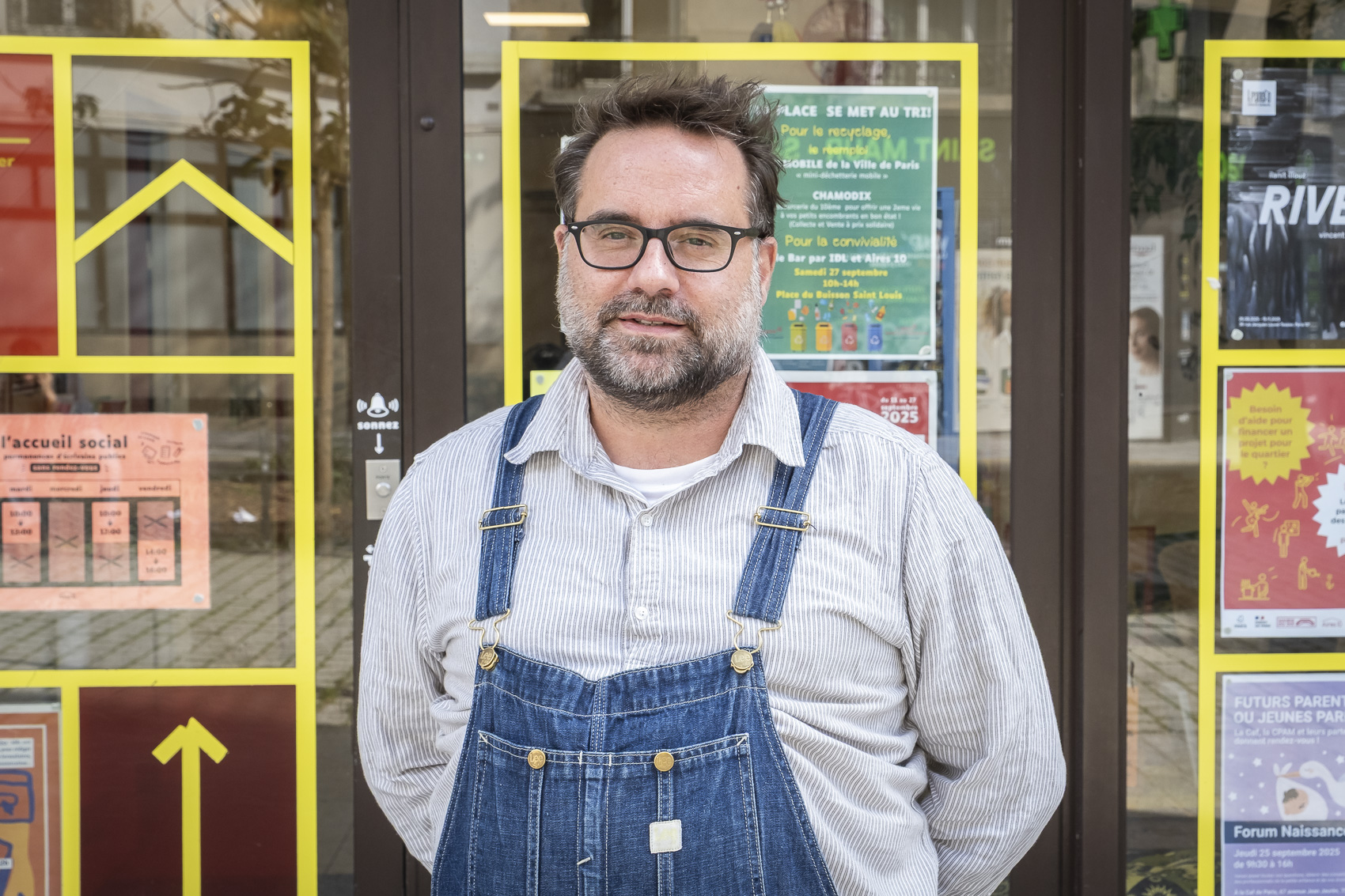 Homme en salopette devant des affiches