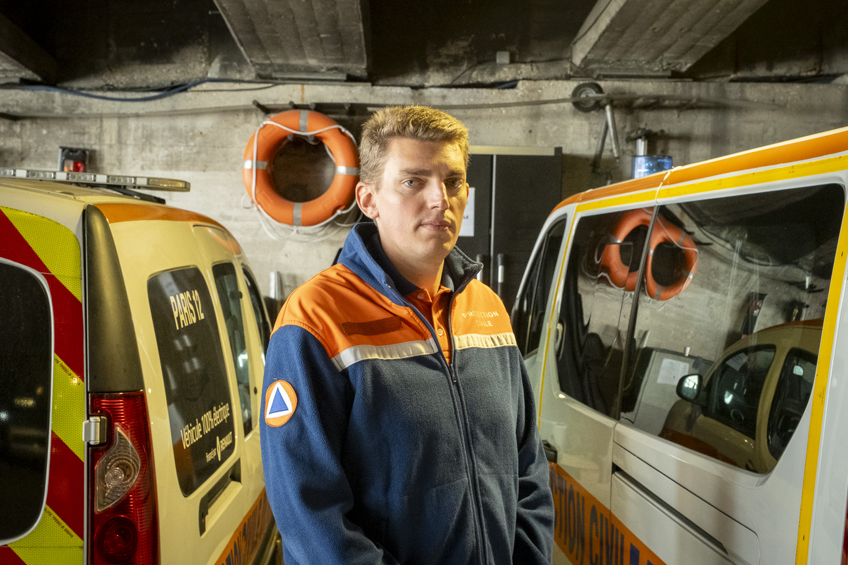 Un secouriste pose devant deux véhicules