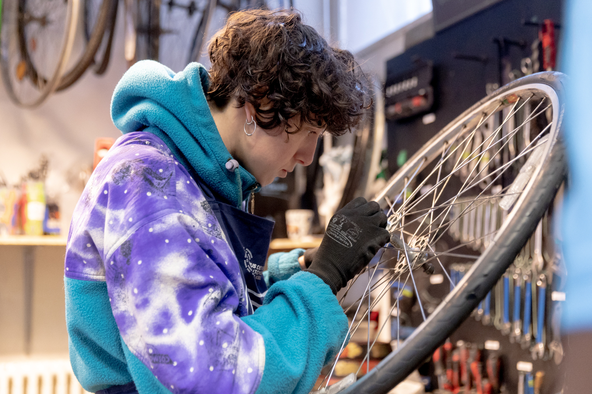 Une personne répare son vélo dans une recyclerie. 