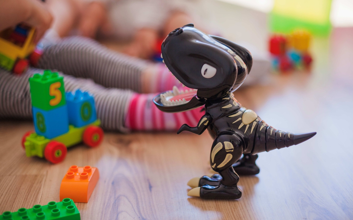 un dinosaure en plastique sur du parquet