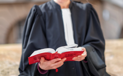 focus sur un code Dalloz tenu par un avocat en robe au second plan