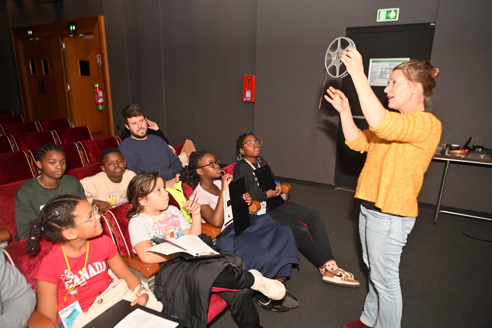 La médiatrice culturelle de la cinémathèque montre une bobine de film aux enfants