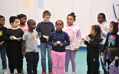 une groupe de 10 enfants sont alignés pour jouer leur pièce de théâtre devant leurs camarades