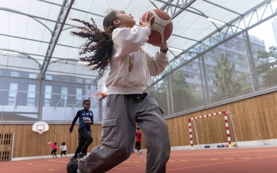 Une jeune fille joue au basket dans la Halle sportive Dunois