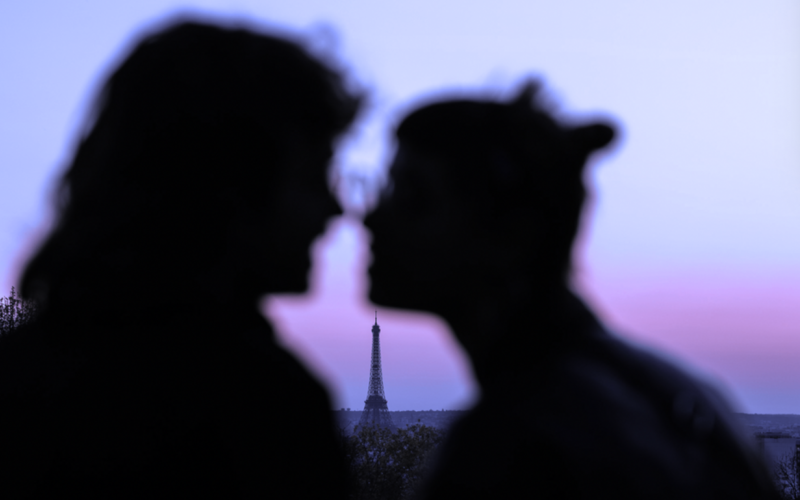Silhouette floue d'amoureux en premier plan avec la tour Eiffel en arrière plan.