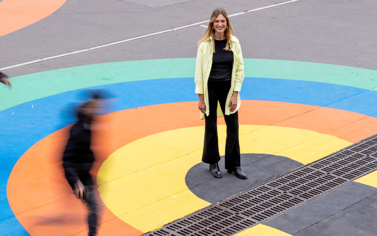 Une jeune femme, artiste peintre pose au milieu d'une fresque monumentale au sol