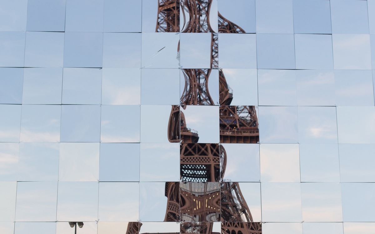 Reflet destructuré de tour Eiffel dans les vitres miroirs d'un immeuble parisien.