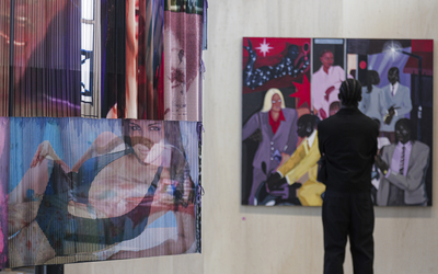 Un homme de dos observe des oeuvres exposées au mur