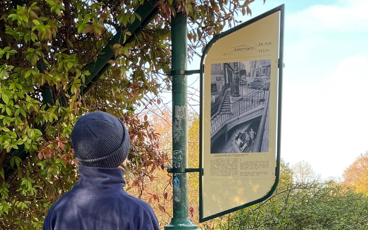 Une personne regarde le parcours Perec sur la rue Vilin (20e)