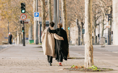 Deux personnes se promènent bras dessus, bras dessous.