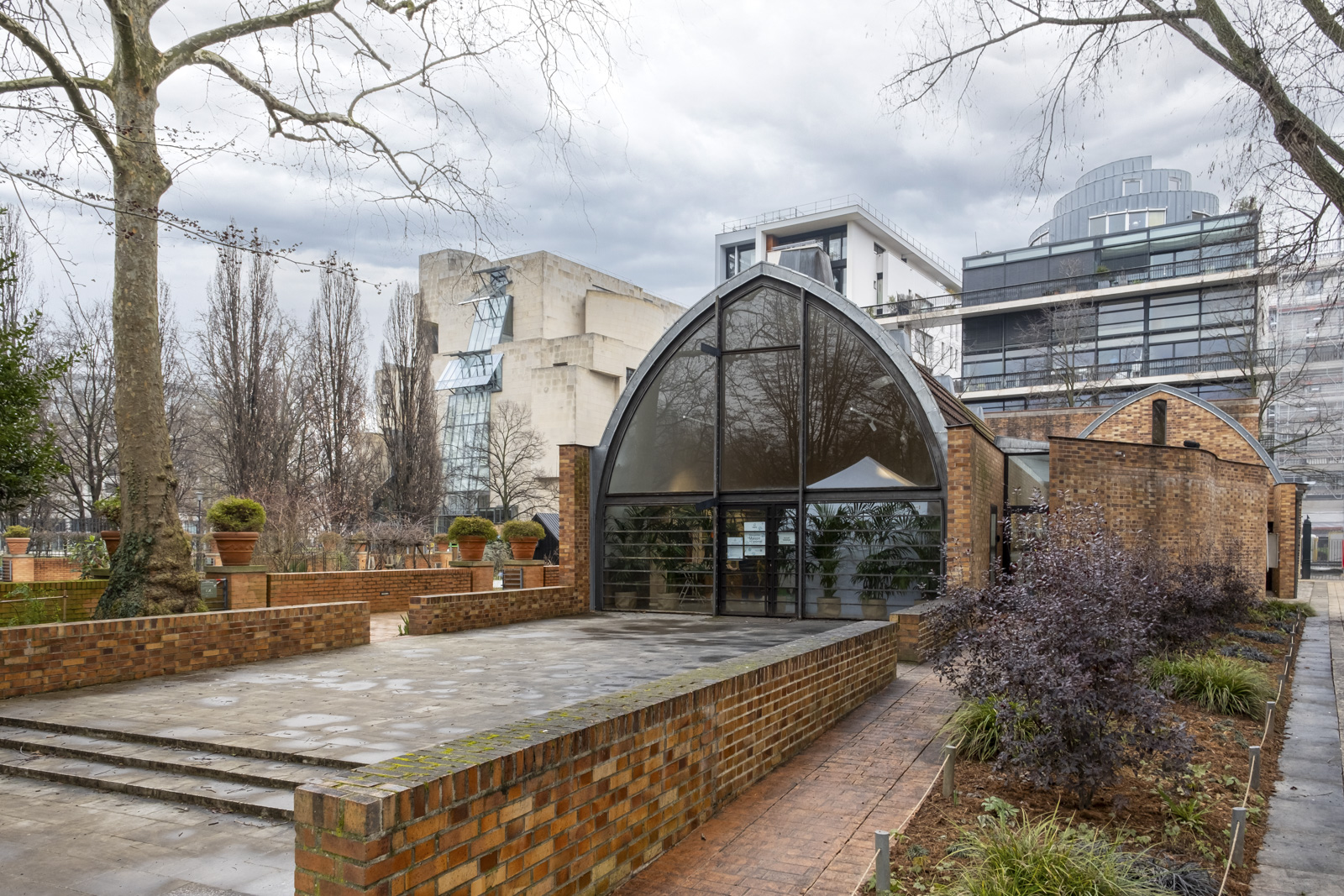 Un bâtiment en forme de chai vu depuis un jardin