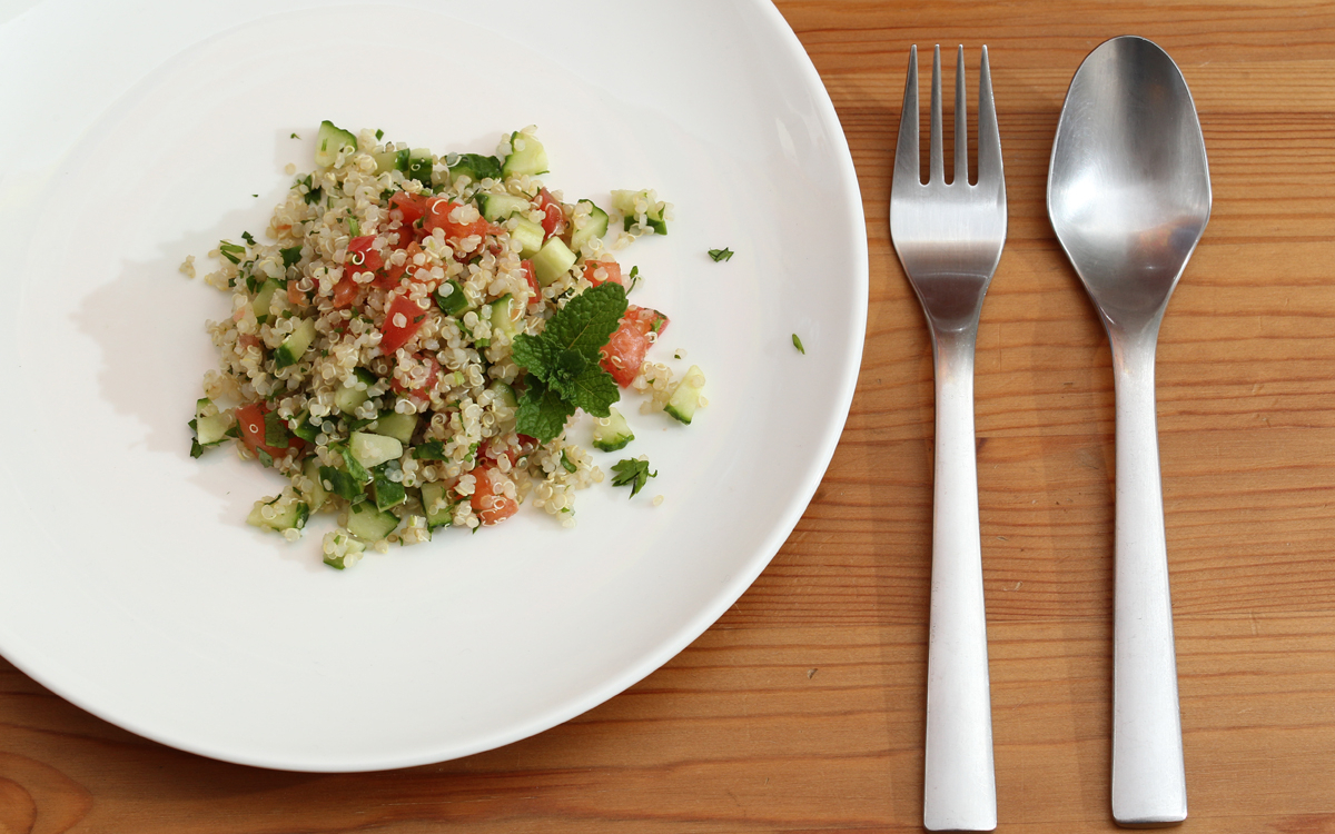 Quinoa façon taboulé dans une assiette avec des couverts à sa droite