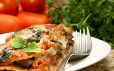 Gros plan sur une assiette de lasagnes au poireau avec une fourchette sur sa droite..