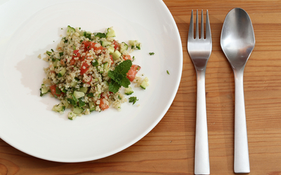 Quinoa façon taboulé dans une assiette avec des couverts à sa droite
