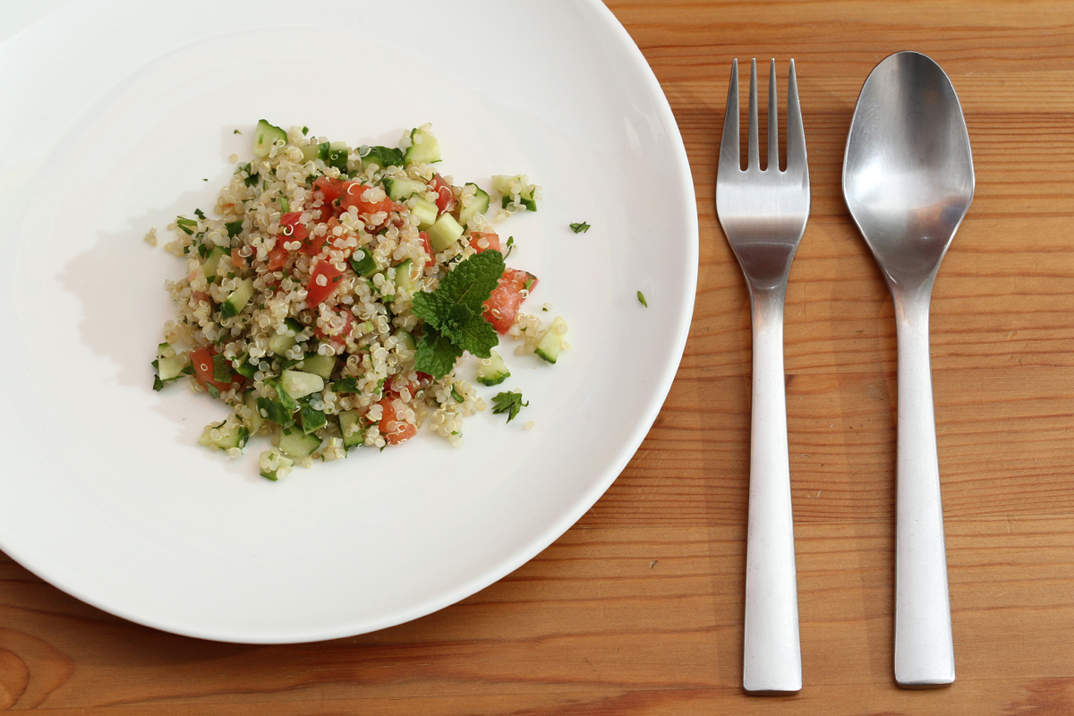 Quinoa façon taboulé dans une assiette avec des couverts à sa droite