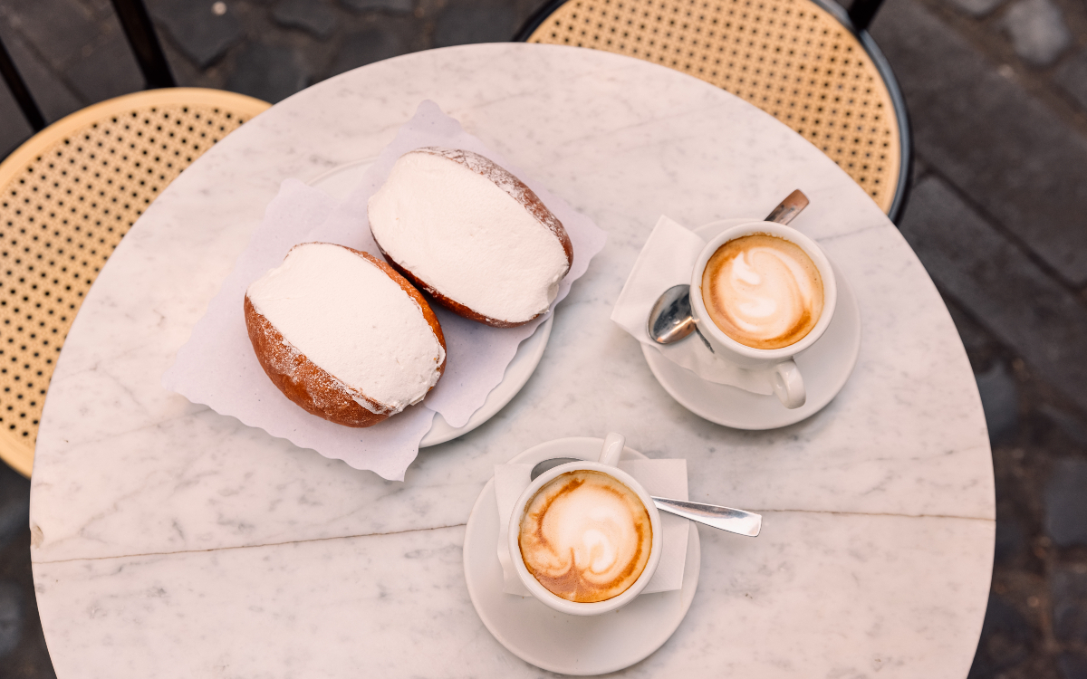 Une table avec un maritozzi et deux cappuccino.
