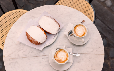 Une table avec un maritozzi et deux cappuccino.