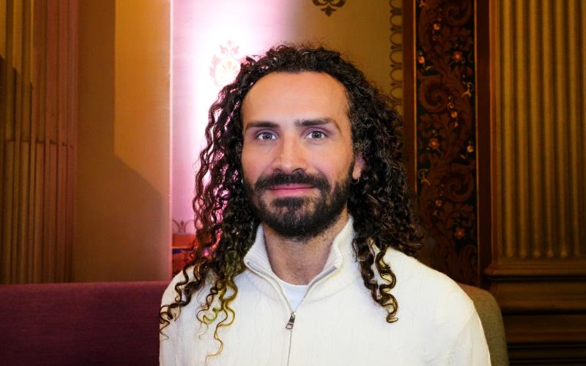 un homme avec les cheveux bouclés et un pull blanc