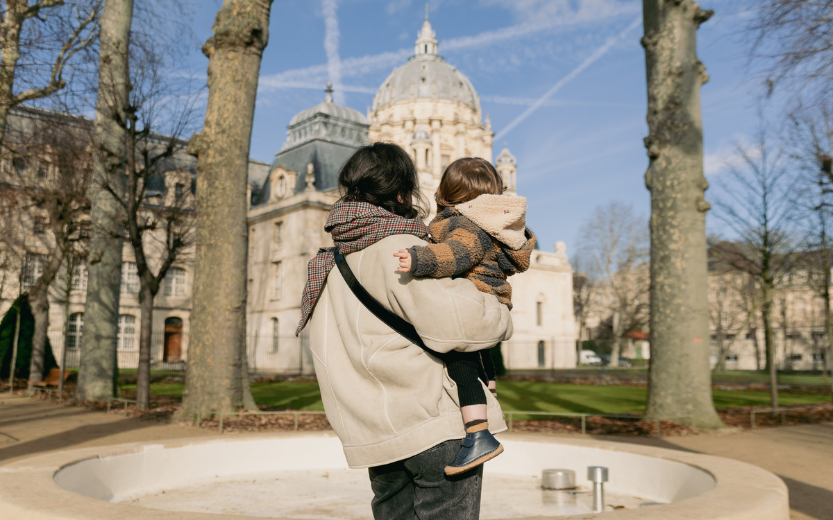 Une personne avec un enfant dans les bras dans les jardins du Val-de-Grâce, 5e.
