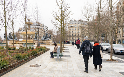 Des personnes se promènent sur la place Félix Eboué.