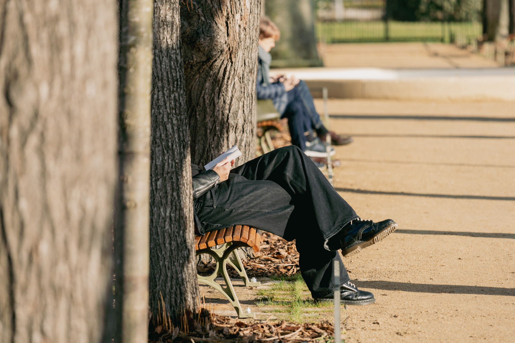 Des personnes lisent et se reposent sur les bancs public des jardins du Val-de-Grâce, 5e.