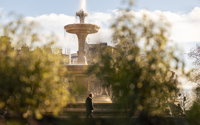 Vue sur la fontaine delLa place Félix Eboué à travers la végétation. 