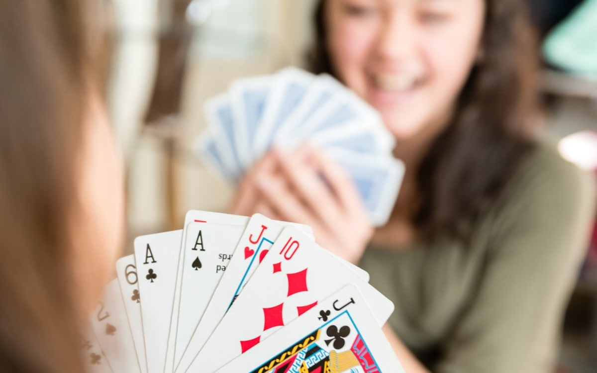 Deux jeunes jouant aux cartes. Nous pouvons voir les cartes d'un des deux joueurs.