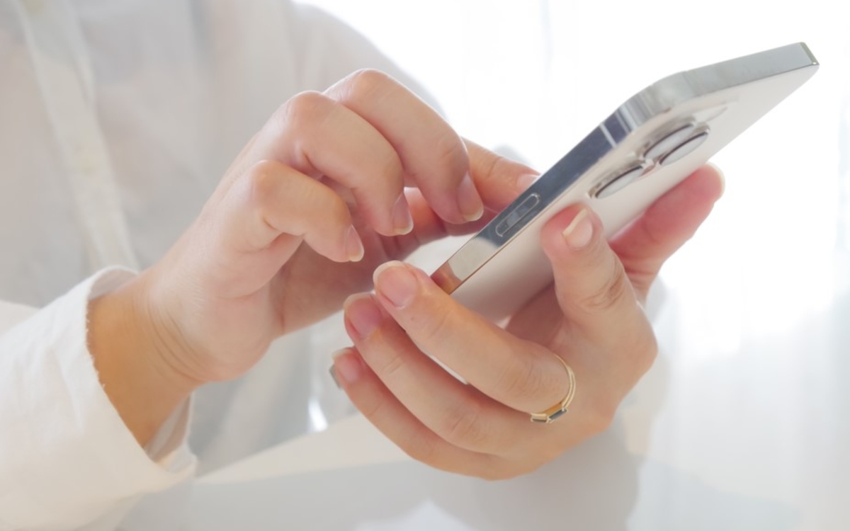 Photographie des mains d'une femme utilisant un smartphone pour faire une recherche