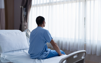 Femme regardant par la fenêtre depuis un lit d'hopital