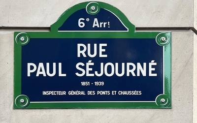 Photographie d'une plaque affichant "6e Arrondissement, Rue Paul Séjourné" sur un mur